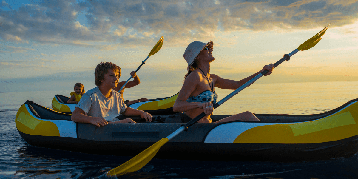 woman and young boy kayaking on water at sunset